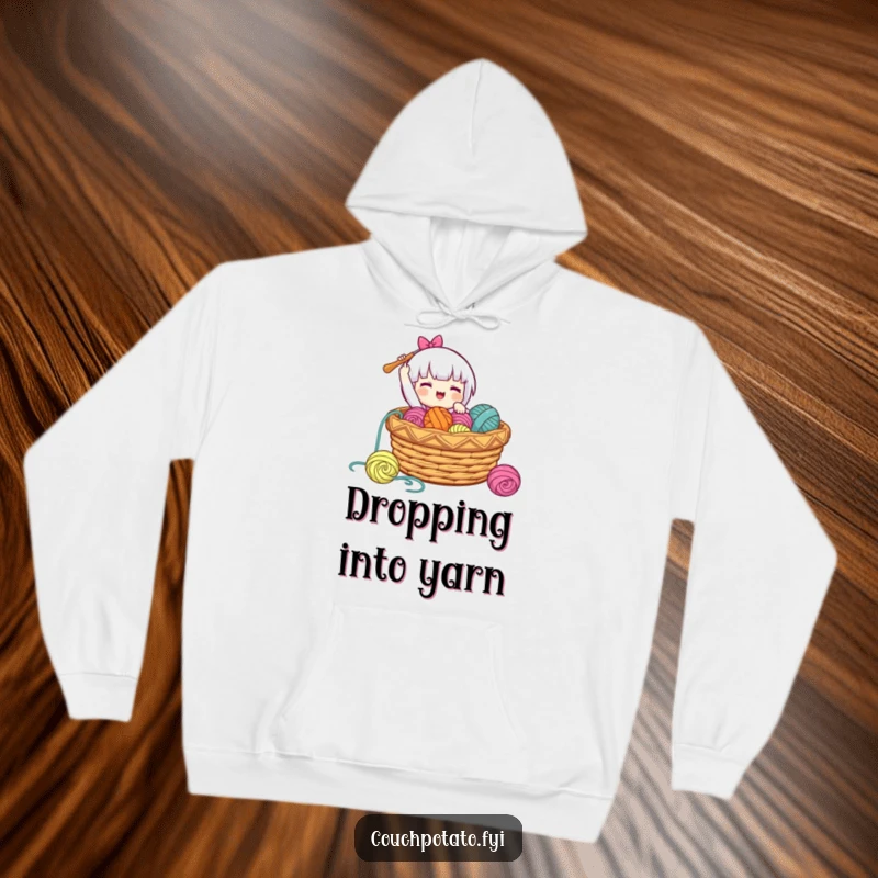 Funny, cozy hoodie depicting a character gleefully dropping a crochet hook into a basket full of yarn, perfect for relaxing.